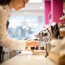 Barista at a bright café counter preparing a morning order